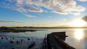 A waterfront scene with boats docked near a concrete barrier, a clear sky, and the sun setting on the horizon. - Beautiful 3-person apartment facing the main beach (Saint-Georges-de-Didonne)