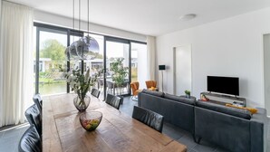 Una sala de estar moderna con una mesa de comedor de madera, un sofá gris y un televisor de pantalla plana.