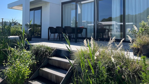 Una casa moderna con patio, mobiliario exterior y ventanas amplias.