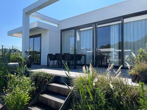 A modern house with a patio, outdoor seating, and large windows.