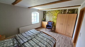 Une chambre à coucher comprenant un lit, une chaise, une armoire, un radiateur et une fenêtre.