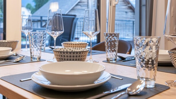 A dining table set with glassware, bowls, and cutlery, with a view of a building outside. - Apartment Near ski Area in Groebming (Groebming)