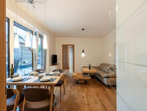 Un salon moderne avec un coin repas, un plancher en bois et de grandes fenêtres.