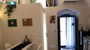 Un espacio habitable compacto con comedor, cocina y una puerta que da a otra habitación.