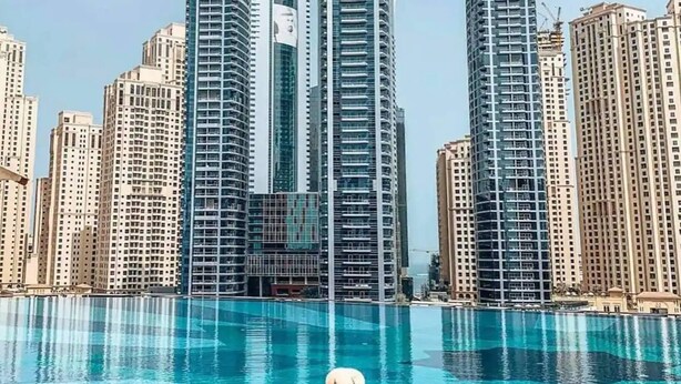 Una persona en una piscina con edificios altos al fondo.