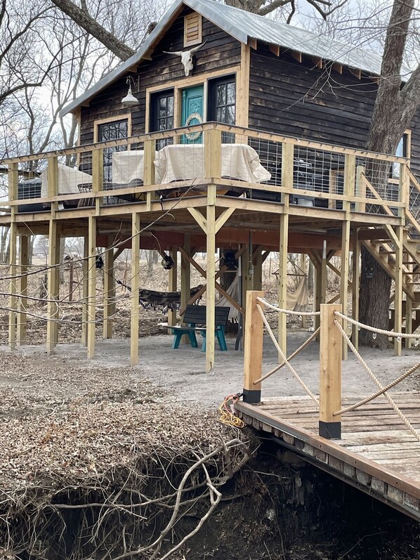 A wooden cabin with a balcony and a covered deck area. - Fun & Magical Treehouse (Coweta)