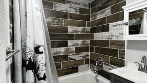 Un baño con bañera, cortina de ducha y lavabo con espejo.