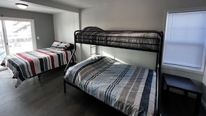Un dormitorio con literas, una mesita pequeña y una ventana con persianas.