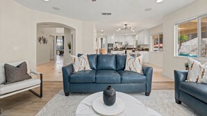 A spacious living room with a blue leather sofa, a white coffee table, and a ceiling fan. - Villa Paradiso (El Cajon)