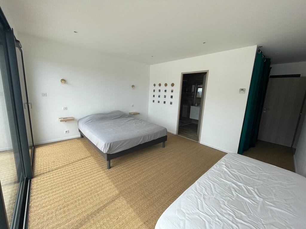 Une chambre d’hôtel avec un grand lit, une petite table de chevet, une horloge murale et une porte donnant accès à la salle de bain.