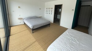 Una habitación de hotel con una cama grande, una mesita de noche pequeña, un reloj en la pared y una puerta que da al baño.