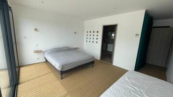 Une chambre d’hôtel avec un grand lit, une petite table de chevet, une horloge murale et une porte donnant accès à la salle de bain.
