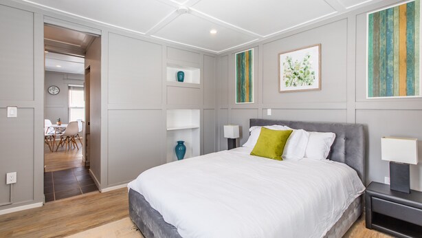 Un dormitorio moderno con una cama grande, mesitas de noche y obras de arte en las paredes.