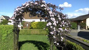 A garden with a floral archway, a well-maintained lawn, and a house in the background. - Double time-out on one floor. Time-out 1 and time-out 2 together (Rattelsdorf)