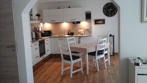 A compact kitchen with white cabinets, a microwave, and a clock on the wall. - Double time-out on one floor. Time-out 1 and time-out 2 together (Rattelsdorf)