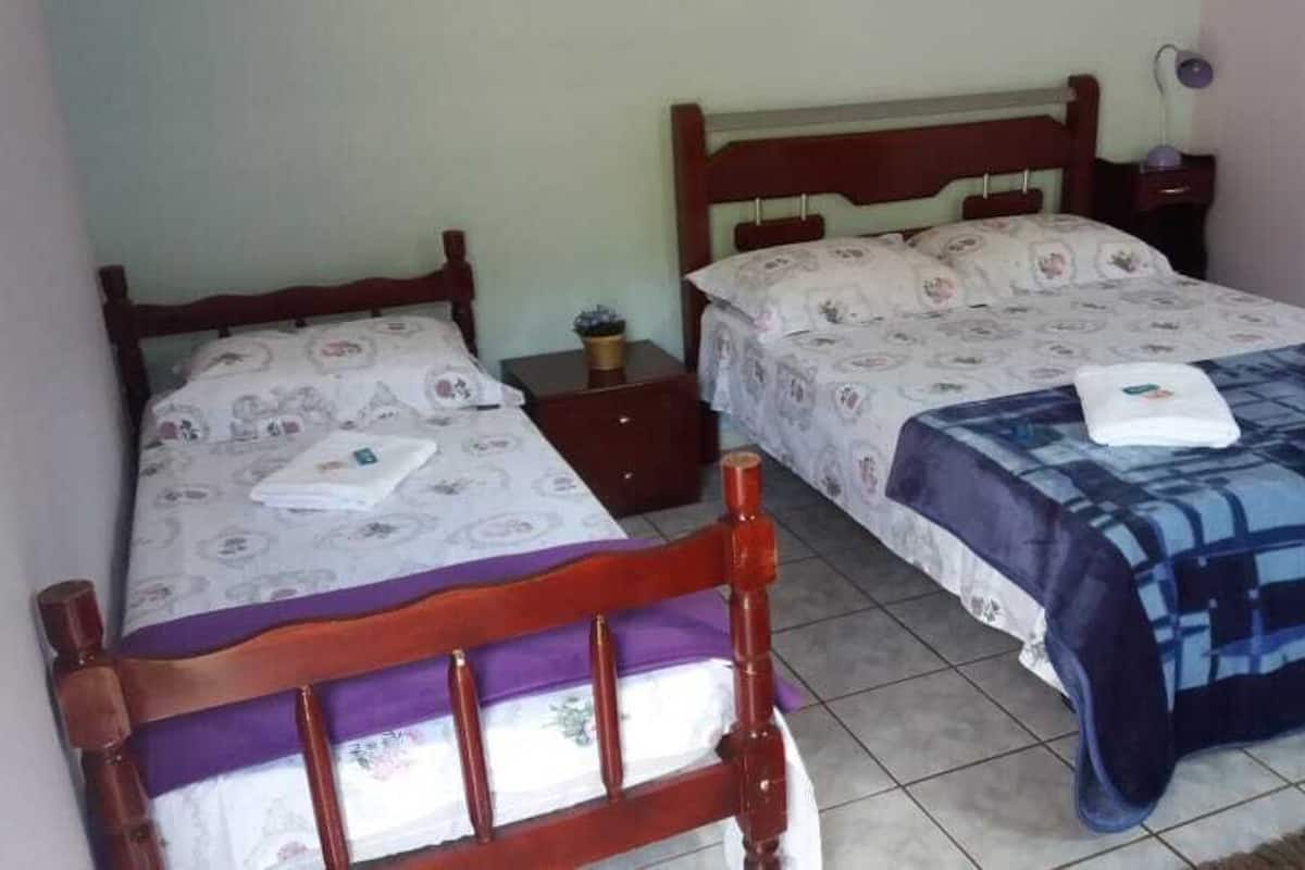 Two wooden beds with floral bedding, a small bedside table, and a nightstand with a lamp.