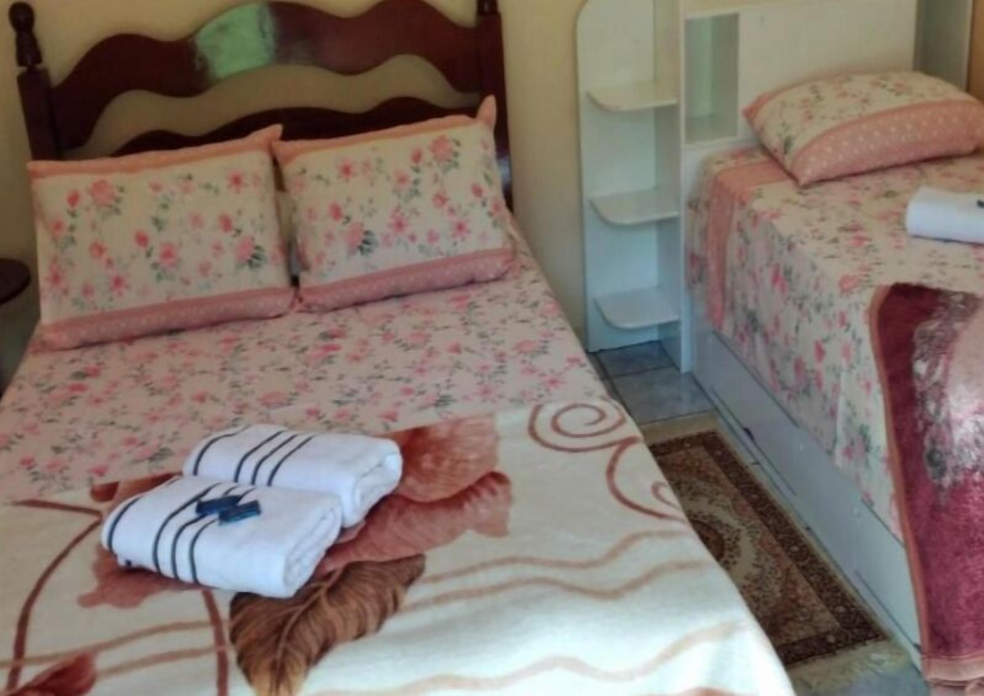A bedroom with a bed, two pillows, a bedside table, and a small nightstand.