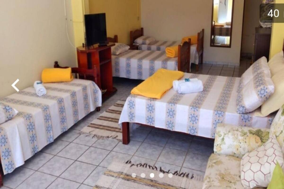 A hotel room with two single beds, a sofa, a TV, and a small table.