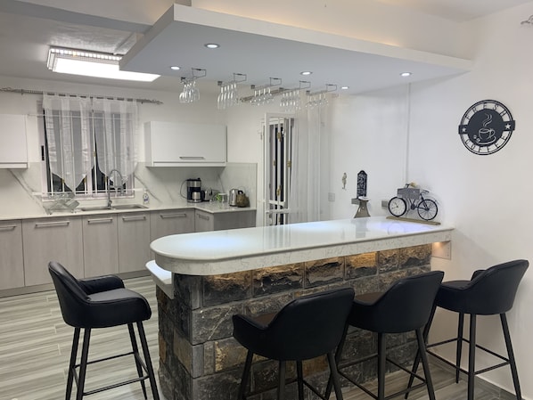 Une cuisine moderne avec un îlot central, des tabourets de bar et une horloge au mur.