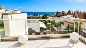 Un balcon offrant une vue dégagée sur la mer, un sol carrelé et deux objets sphériques blancs.