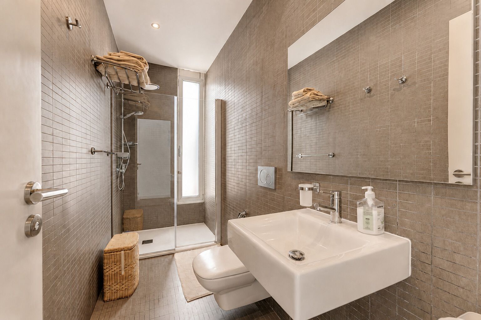 A modern bathroom with a shower, toilet, and sink.