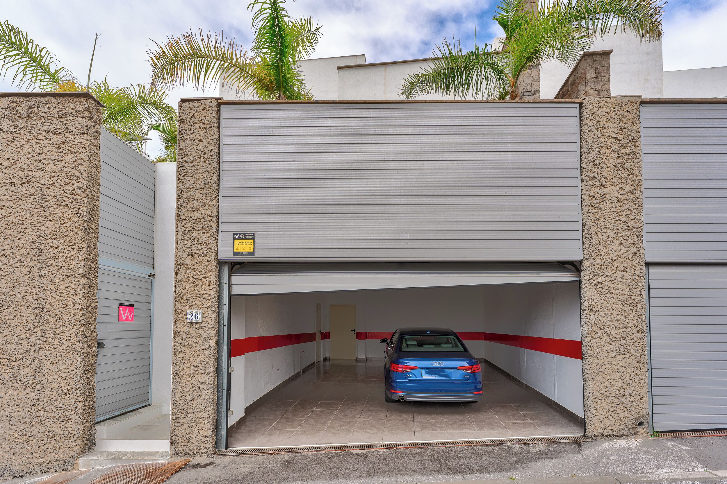 A parking garage with a blue car, a red stripe, and a door marked with a 'W'.