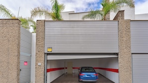 Un parking avec une voiture bleue, une bande rouge et une porte marquée d’un « W ».