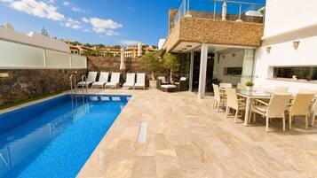 Une piscine avec des chaises longues et un espace repas comprenant des tables et des chaises.