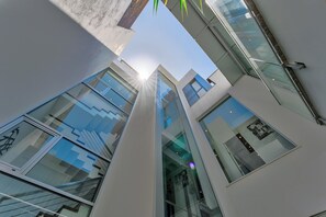 A modern building with multiple floors, large windows, and a clear view of the sky.