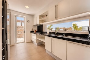 A modern kitchen with a large window, a built-in oven, and a view of the city. - 5BR Villa in Costa Adeje with Private Pool (Costa Adeje)