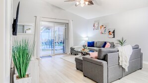 Ein modernes Wohnzimmer mit grauem Sofa, Couchtisch und Deckenventilator.
