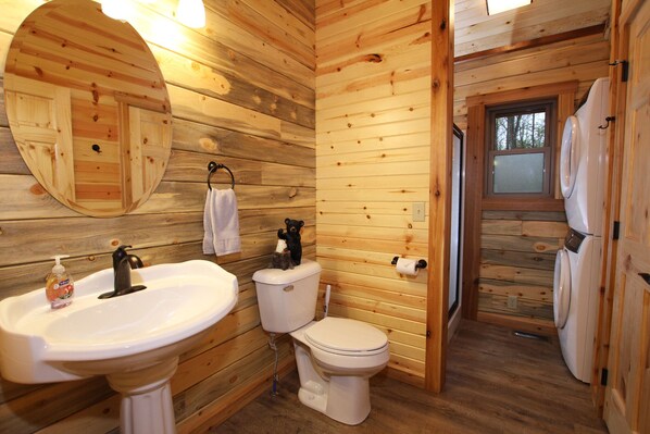 A wooden cabin bathroom with a sink, toilet, and mirror.