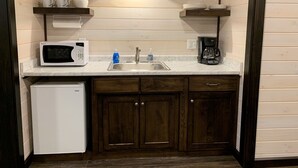 A compact kitchen with a microwave, coffee maker, and sink.