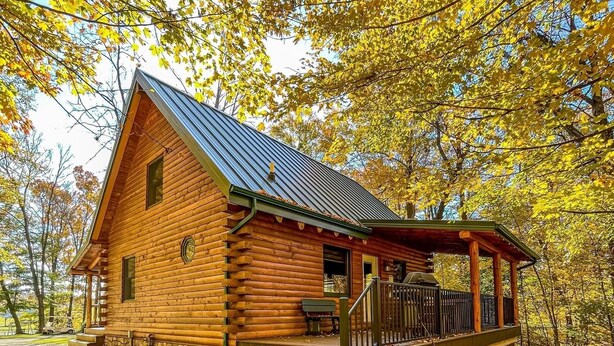 A log cabin with a porch and steps leading to a deck. - Cozy Pine at Tranquil Acres (Millersburg)