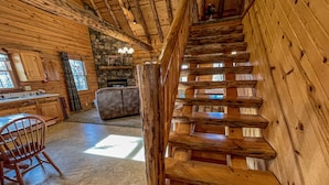 A wooden interior with a staircase, a fireplace, and a dining area. - Cozy Pine at Tranquil Acres (Millersburg)
