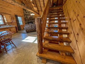 Un intérieur en bois avec un escalier, une cheminée et un coin repas.