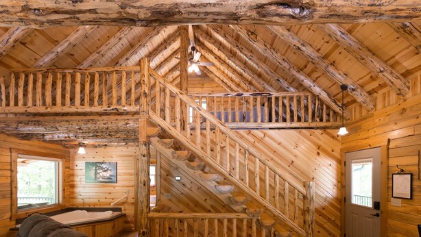 Ein Holzblock-Interieur mit einer zentralen Treppe, einer Couch und einem Fenster mit Blick.