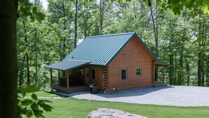 Eine Blockhütte mit Metalldach, einer Veranda und einer Schotterzufahrt.