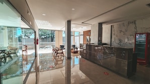 Eine moderne Lobby mit Glastür, Empfangstresen und Sitzgelegenheiten.