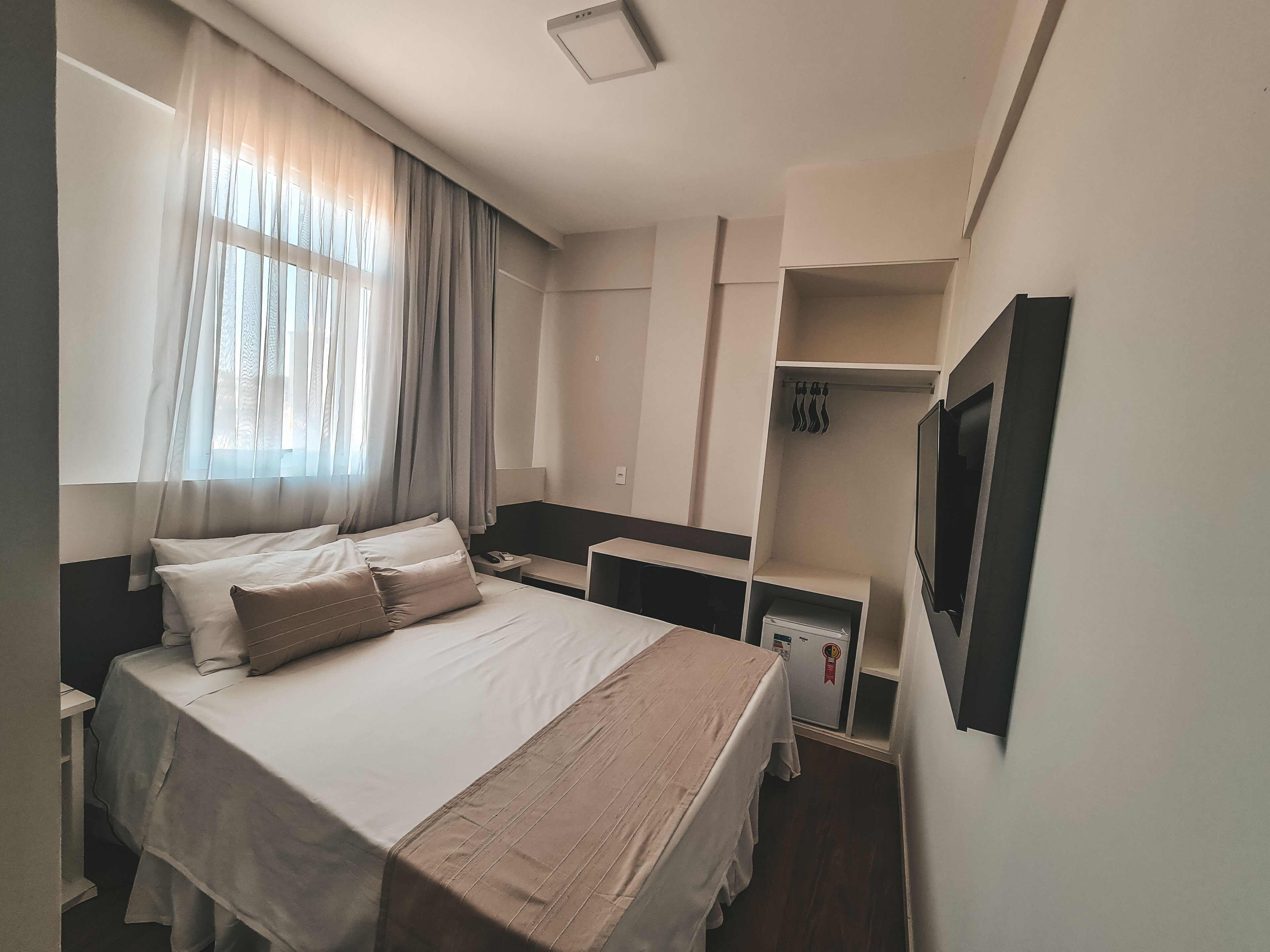 Una habitación de hotel con cama, mesitas de noche, escritorio, armario y televisor.