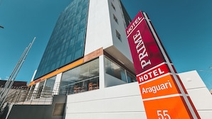Ein modernes Hotelgebäude mit auffälligem Schild für das Prime Hotel Araguari, das eine Glasfassade und eine weiße Außenverkleidung aufweist.