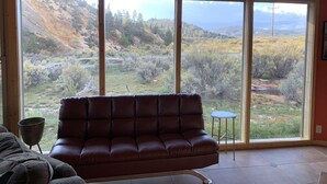 A room with a large window offering a view of a mountainous landscape. - Panoramic views on 50 private acres! (Escalante)
