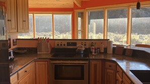 A kitchen with wooden cabinets, a stove, and a sink. - Panoramic views on 50 private acres! (Escalante)
