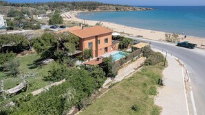 A coastal property with a swimming pool, a road, and a beach.