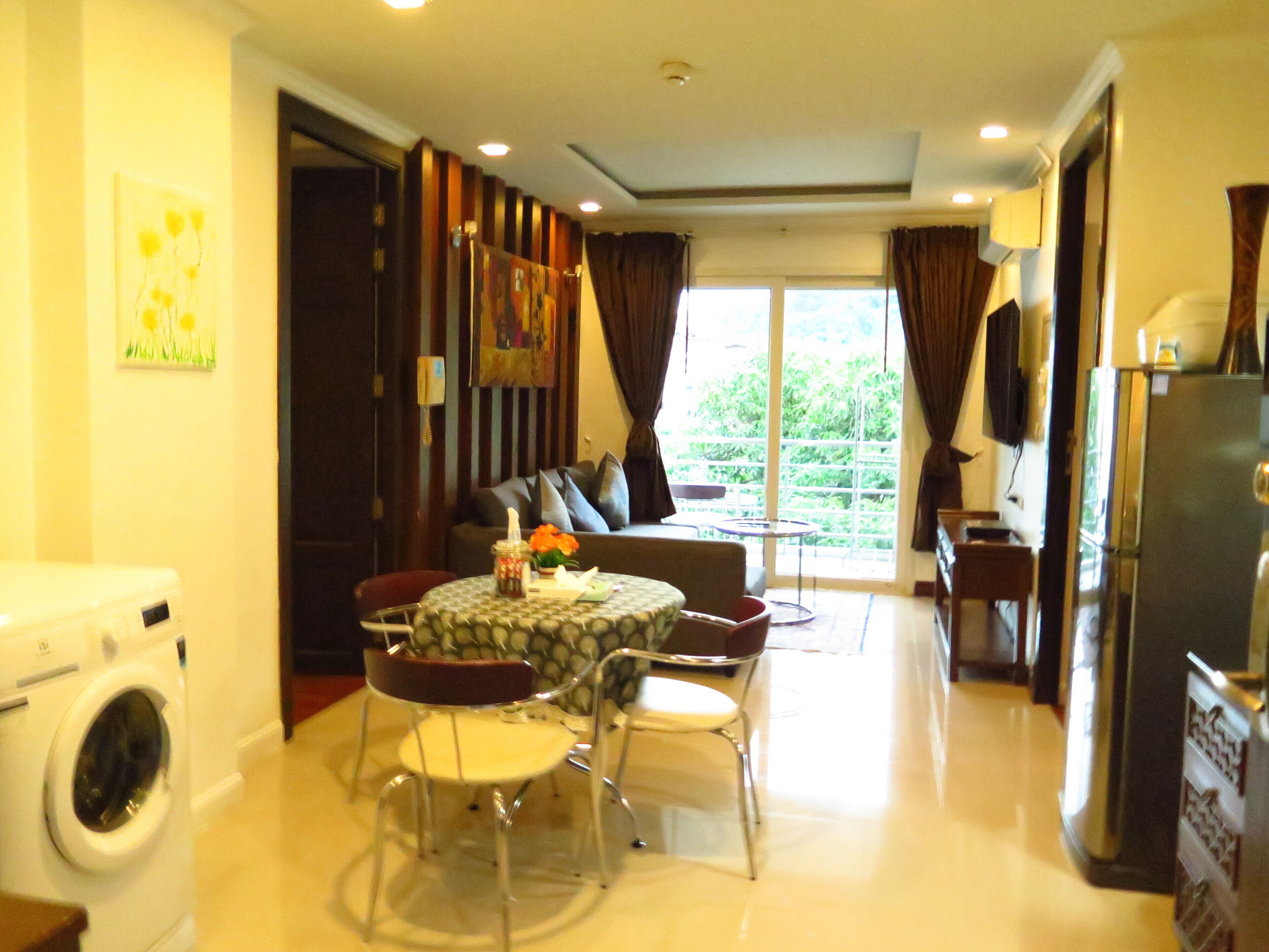 A compact living space with a dining area, a sofa, a small table, and a washing machine.
