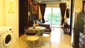 A compact living space with a dining area, a sofa, a small table, and a washing machine.