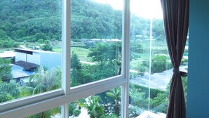 A room with a large window overlooking a lush green landscape and a distant building.