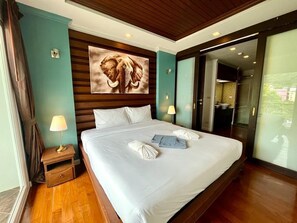 Relax in this serene space with a large bed, nightstand, and wall-mounted artwork, surrounded by a sliding glass door leading to an outdoor area.