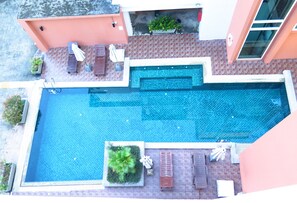 Relax by the pool surrounded by a deck with a patterned tile floor and a potted plant.