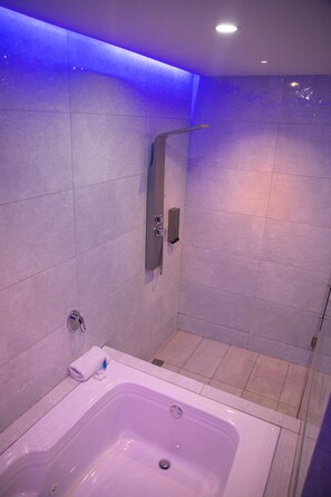 A modern bathroom with a bathtub, a shower area, and a glass shower enclosure. - Hotel ByHours Circunvalar (Barranquilla)